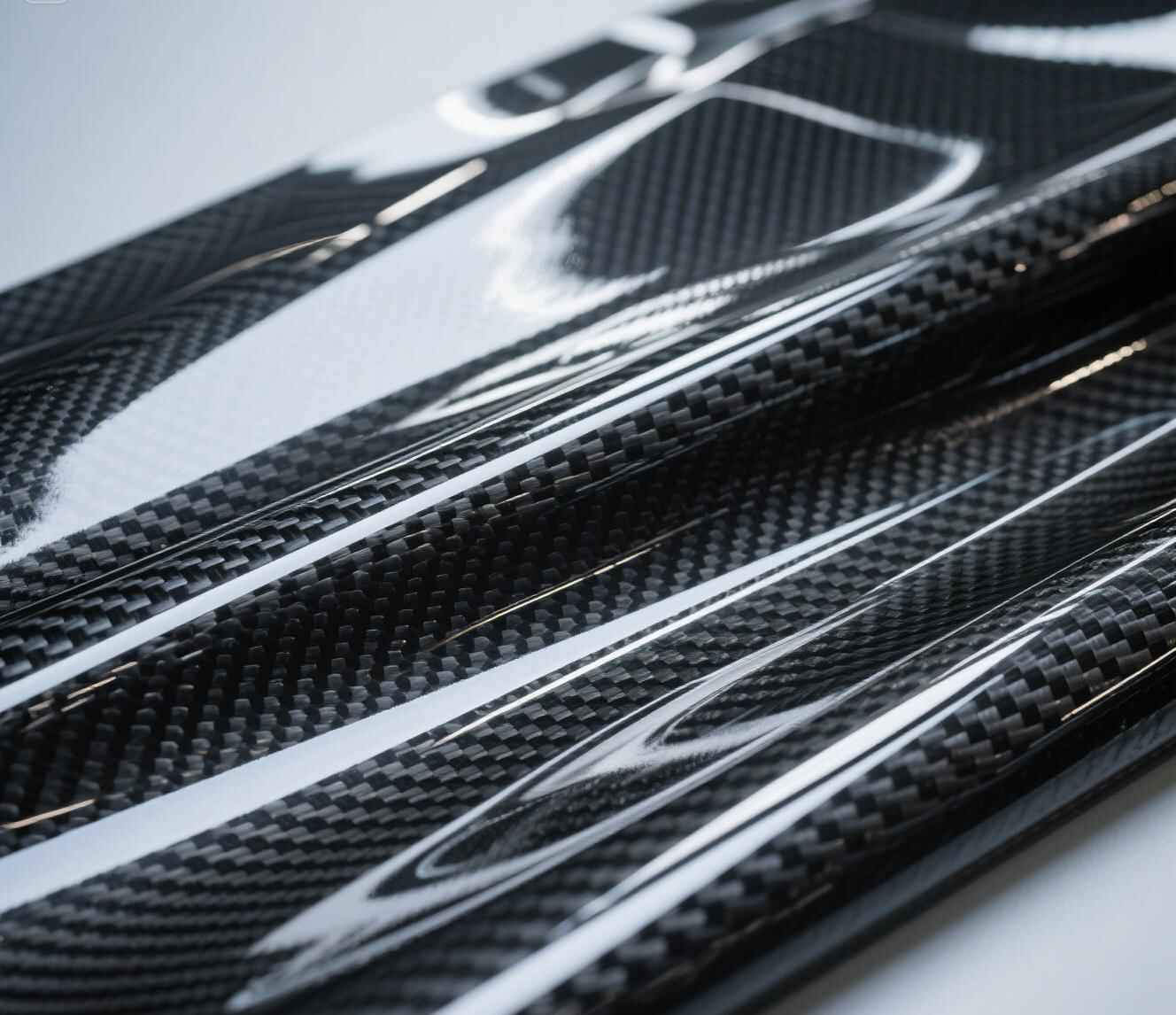 alt="Professional repairing a carbon fiber panel using specialized tools"